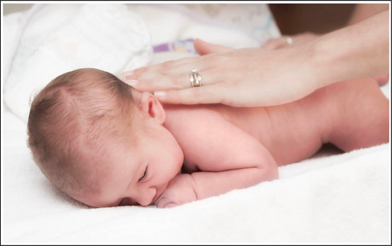 Mother rubbing luminance skincare baby product into infant